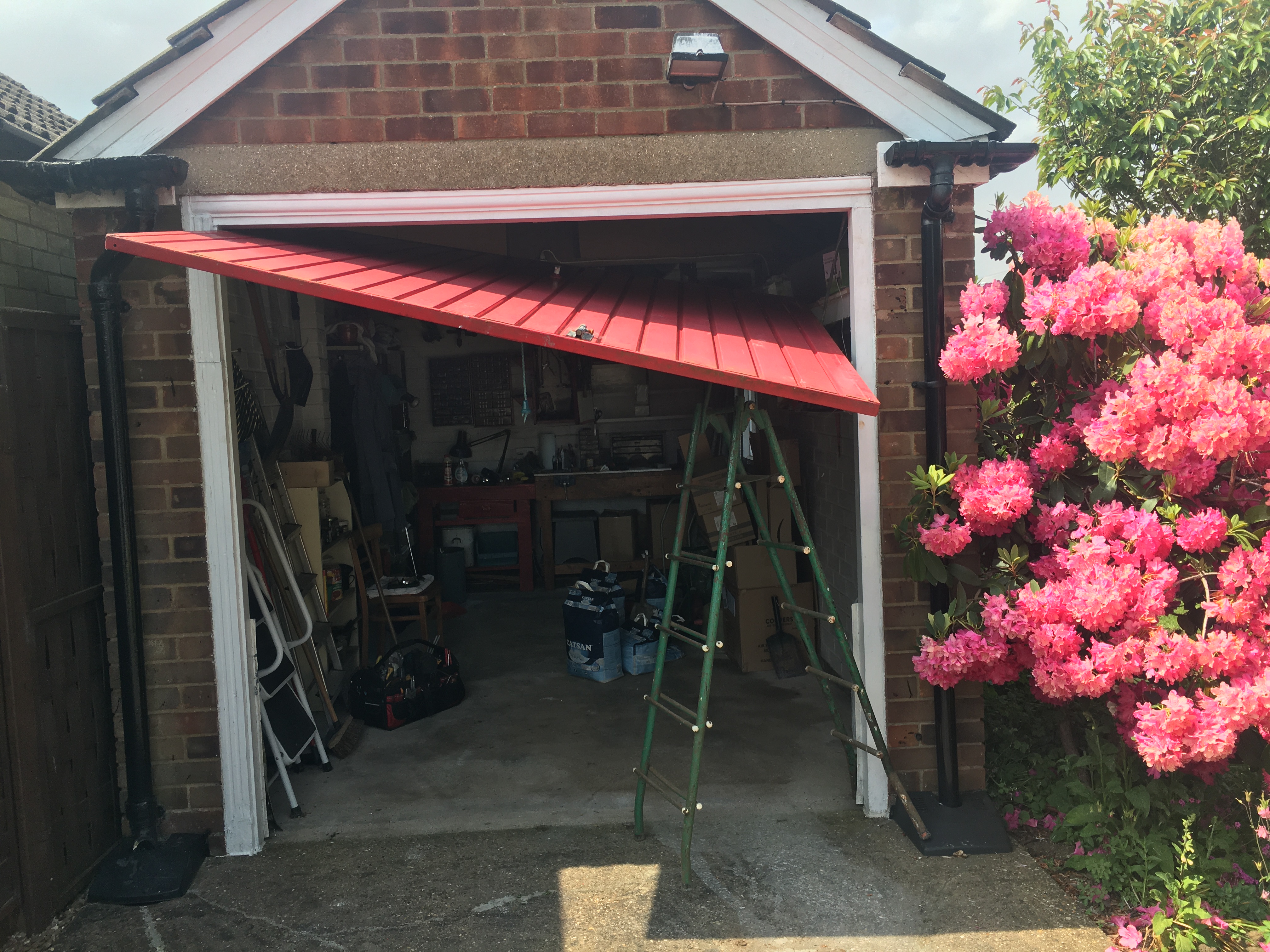 Garage door before repair — collapsed panel hanging off its tracks